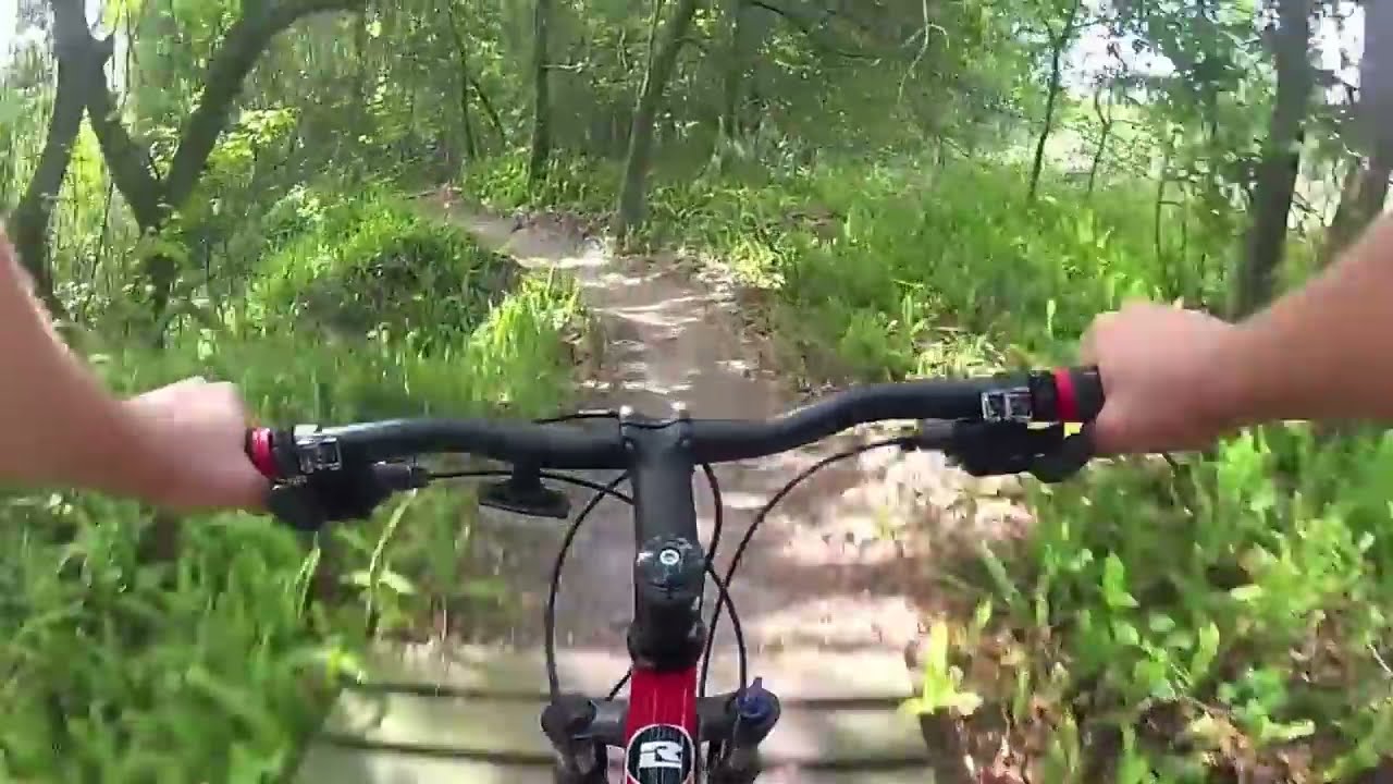 Mountain Biking North Creek at Alafia River State Park 1 Handlebar view rolling onto a wooden bridge through green forest on the North Creek mountain bike trail at Alafia River State Park