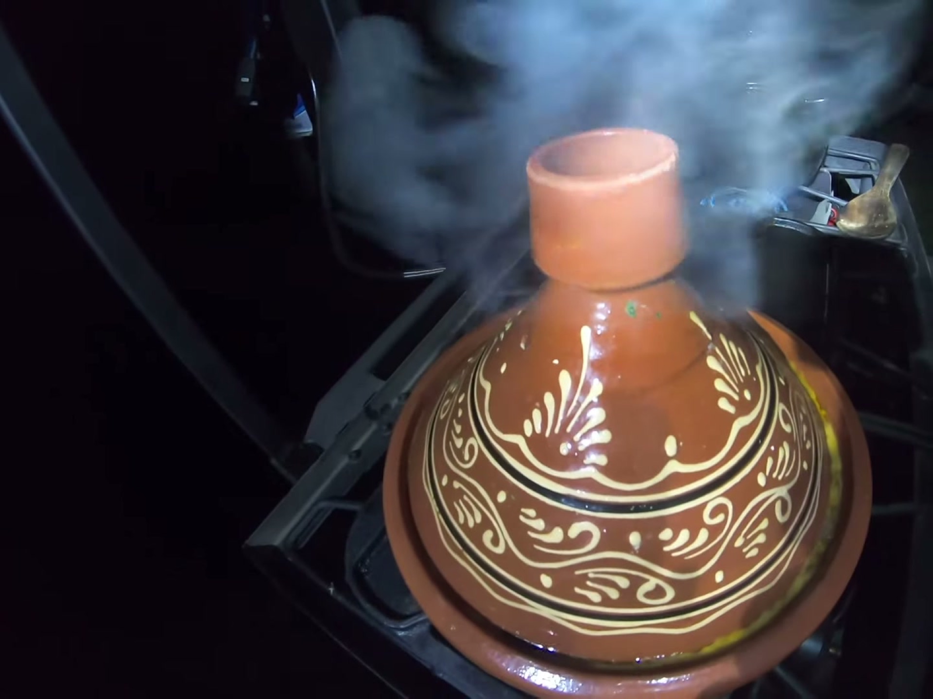 Campsite Cooking: Chicken Tagine with the Overland Crew 1 A decorated clay tagine pot steaming on a camp stove at dusk