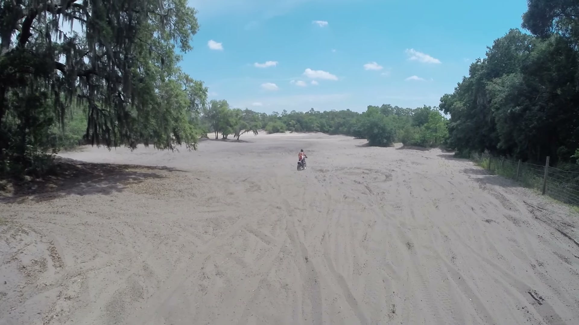 Dirt Biking the Croom Motorcycle Area 1 A dirt bike rider crossing a wide sand wash under a blue sky at the Croom Motorcycle Area in Brooksville, Florida