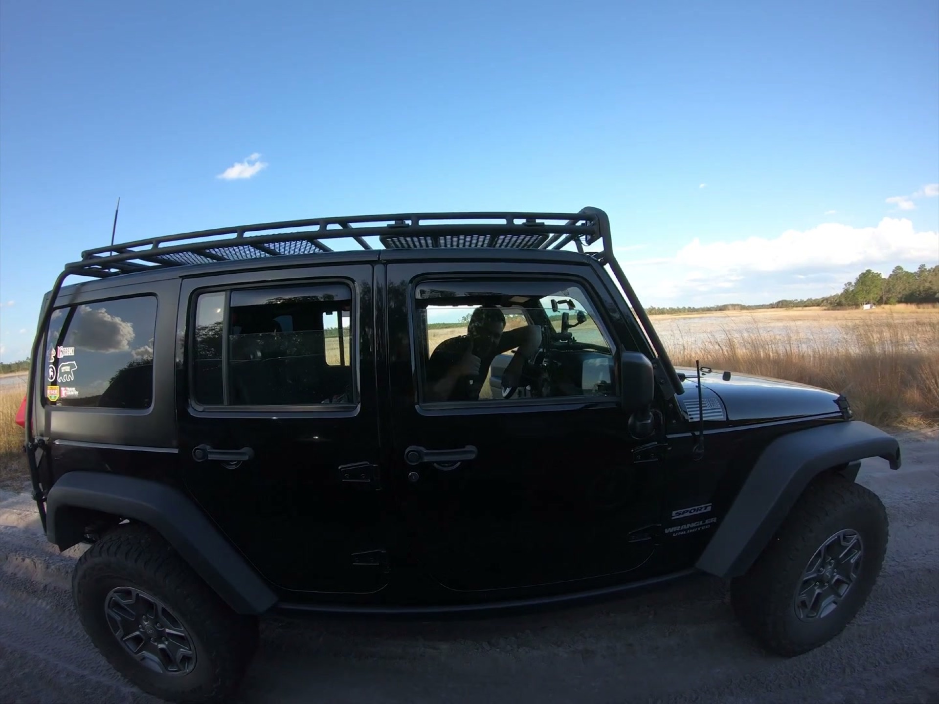 The Rally Point: Overlanding Hopkins Prairie in Ocala 5 A black Jeep Wrangler with a roof rack on the sand road beside Hopkins Prairie